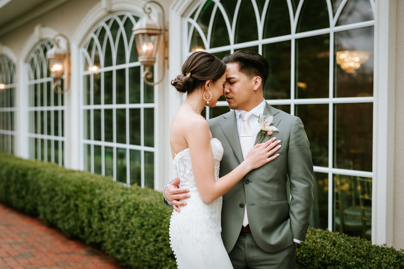 Couple embracing beside the arched ballroom windows