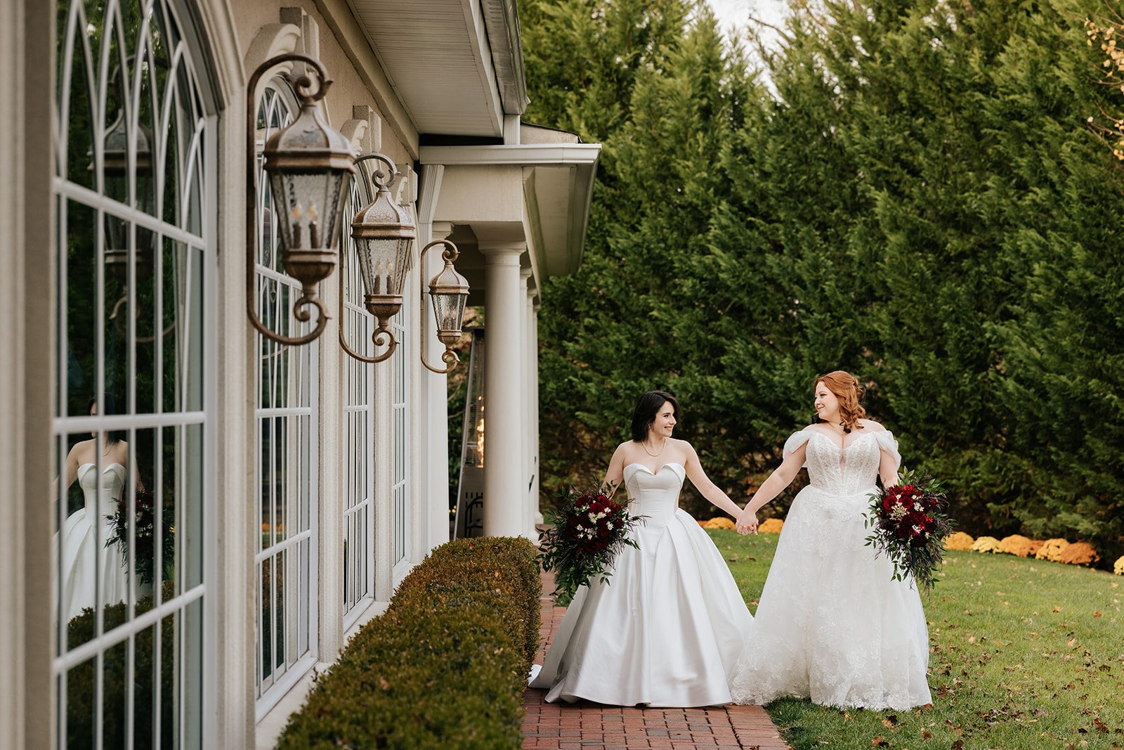 Two brides walking hand in hand past the arched windows